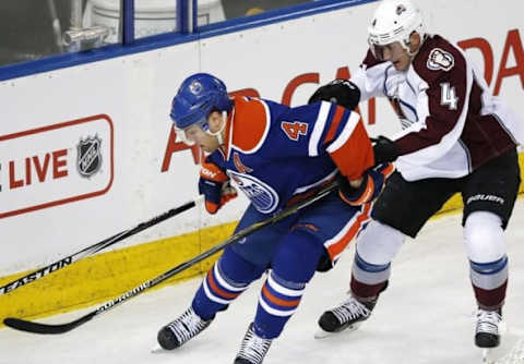 Mar 25, 2015; Edmonton, Alberta, CAN; Edmonton Oilers forward Taylor Hall (4) and Colorado Avalanche defensemen Tyson Barrie (4) battle for a loose puck during the first period at Rexall Place. Mandatory Credit: Perry Nelson-USA TODAY Sports