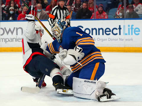 BUFFALO, NY – DECEMBER 11: T.J. Oshie #77 of the Washington Capitals crashes into Ukko-Pekka Luukkonen #1 of the Buffalo Sabres during the first period at KeyBank Center on December 11, 2021 in Buffalo, New York. (Photo by Kevin Hoffman/Getty Images)