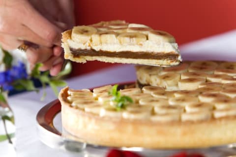 Slice of pie topped with bananas.