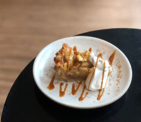 Slice of apple pie with caramel drizzle.