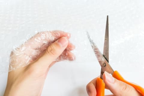 A person cutting Bubble Wrap with scissors.