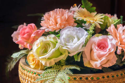 A basket full of pastel-colored fake roses and daises