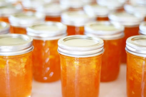 Offset rows of sealed glass canning jars filled with peach preserves