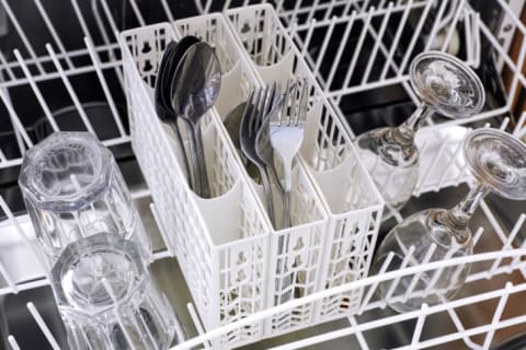 Closeup of forks and spoons in a white dishwasher basket