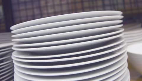 A stack of plain white dishes with a plaid background