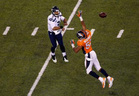 Russell Wilson #3 of the Seattle Seahawks passes as Wesley Woodyard #52 of the Denver Broncos defends during Super Bowl XLVIII at MetLife Stadium on February 2, 2014