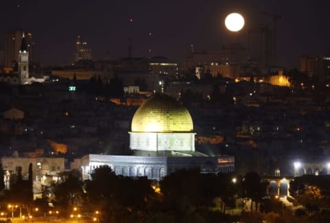 The moon sets behind the city of Jerusalem early on January 31, 2018.