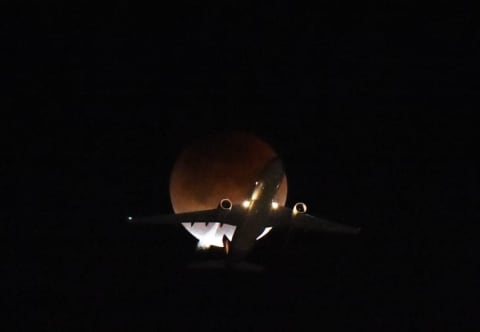 A plane flies passing the moon over Los Angeles, California, on January 31, 2018.