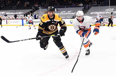 Mar 25, 2021; Boston, Massachusetts, USA; Boston Bruins center Patrice Bereron (37) and New York Islanders defenseman Adam Pelech (3) skate after the puck during the third period at TD Garden. Mandatory Credit: Bob DeChiara-USA TODAY Sports