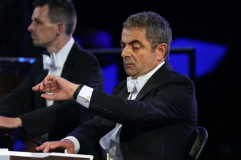 Rowan Atkinson looking at wrist.