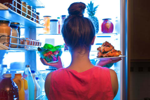 Woman pulling food out of a fridge.