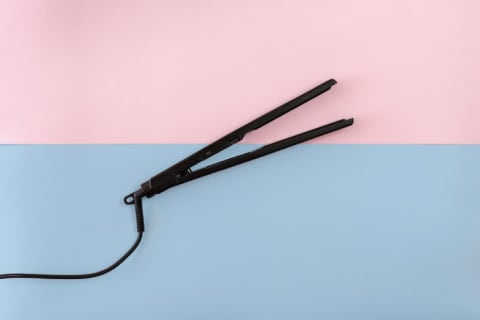 A flat iron against a pastel background.