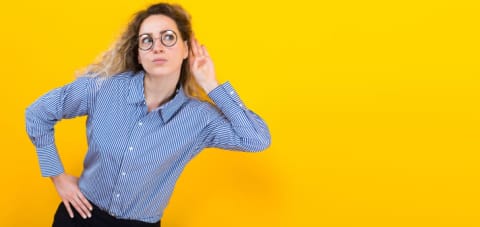 Woman with a hand to her ear to listen.