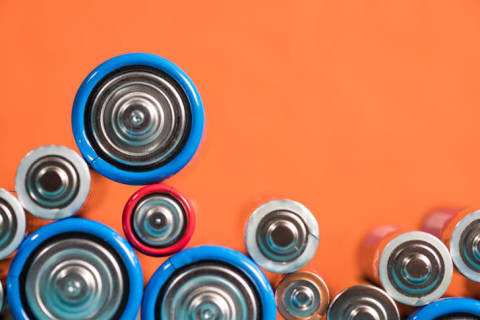 Assorted batteries on an orange background.