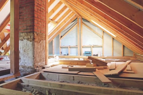 An attic being framed and insulated, with tools splayed out across the floor.