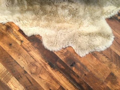 A white sheepskin rug on a rustic wooden floor.