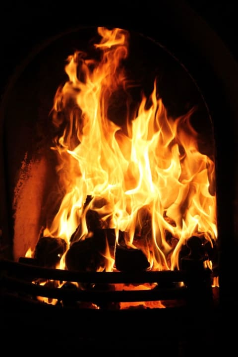 Logs burning in a fireplace with large flames licking off of them.