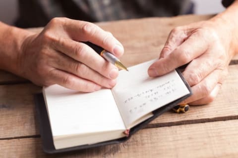 Old man writing in book