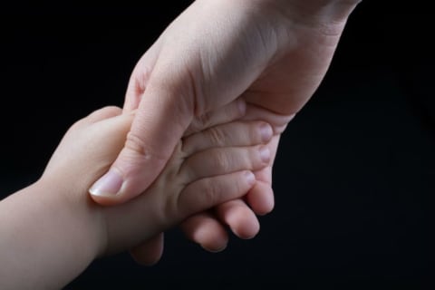 A mother holds her child's hand