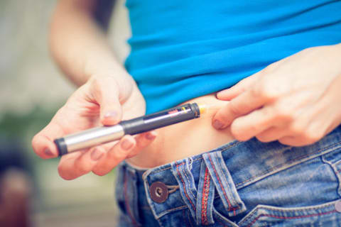 A woman injecting herself with an insulin pen.