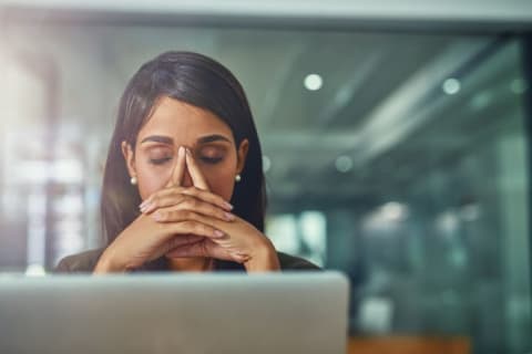 A woman sitting in front of a computer looking tired.