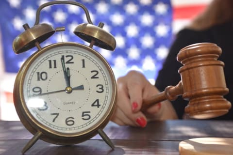 A photo of a judge handing out a sentence with a clock sitting next to her