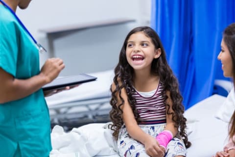 Girl with broken arm laughing in doctor office