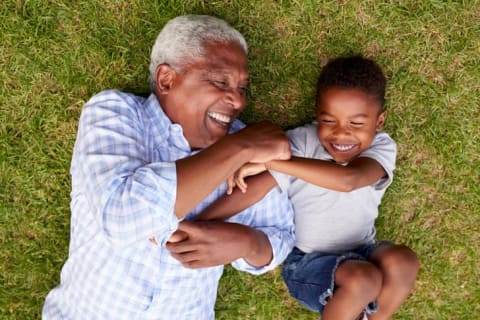 grandfather and grandson laughing on ground