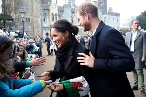 Prince Harry and his fiancee, Meghan Markle, sign autographs and shake hands with children as they arrive to a walkabout at Cardiff Castle on January 18, 2018 in Cardiff, Wales.