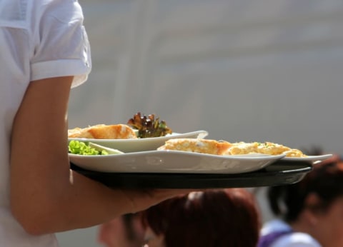 A close shot of a waitress's arm as she carries a tray of food.