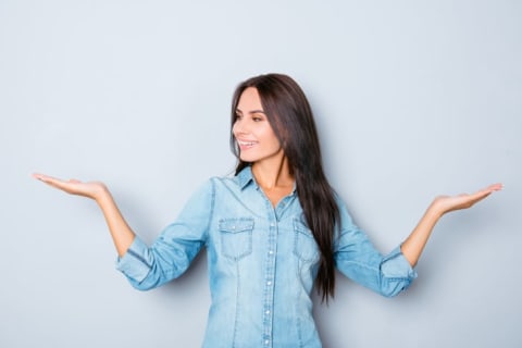 A woman holds out two hands and smiles.