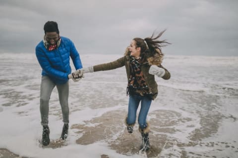 A young couple all bundled up for a winter beach date.