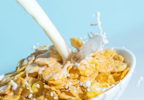 Milk being poured into a bowl of cereal.