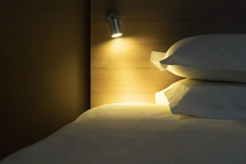 A light shining on a bed and two pillows.