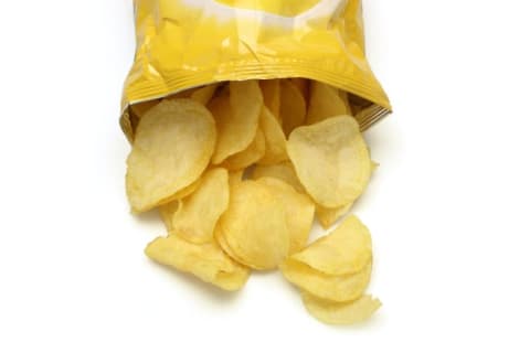 An open bag of potato chips with the chips spilling out.