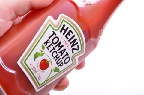 A ketchup bottle being held in someone's hand.