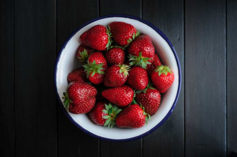 A bowl of strawberries on a wooden table.