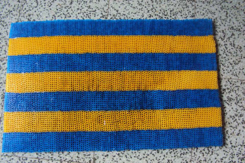 A blue and yellow doormat made out of straws.