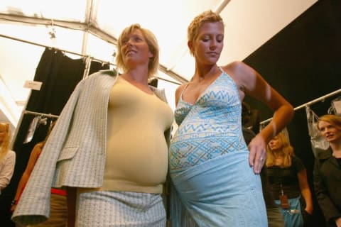 Pregnant models prepare backstage for the Liz Lange Couture Show during NYFW in September 2004.