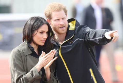 Prince Harry and Meghan Markle stand on the sidelines