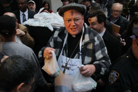 New York's Cardinal Timothy Dolan joins fellow volunteers distributing food at a breadline at St. Francis Assisi on Ash Wednesday in 2012 in New York City.