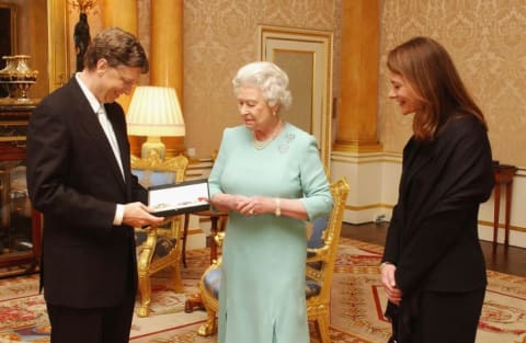 Queen Elizabeth II presents Bill Gates with an honorary knighthood in 2005. His wife, Melinda Gates, would be named an honorary dame in 2014.