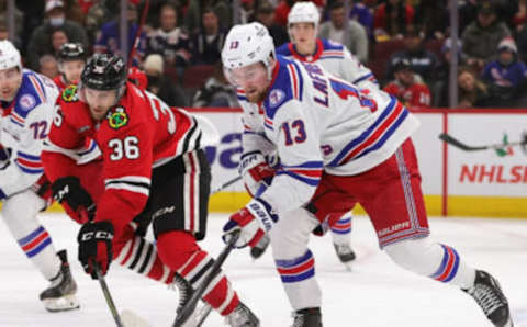 CHICAGO, ILLINOIS – DECEMBER 07: Alexis LafreniÃ¨re #13 of the New York Rangers advances the puck next to Josiah Slavin #36 of the Chicago Blackhawks at the United Center on December 07, 2021, in Chicago, Illinois. The Rangers defeated the Blackhawks 6-2. (Photo by Jonathan Daniel/Getty Images)