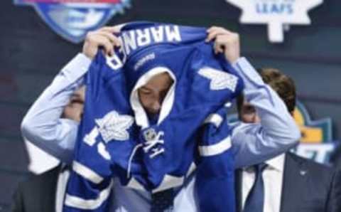 Jun 26, 2015; Sunrise, FL, USA; Mitchell Marner puts on a team jersey after being selected as the number four overall pick to the Toronto Maple Leafs in the first round of the 2015 NHL Draft at BB&T Center. Mandatory Credit: Steve Mitchell-USA TODAY Sports