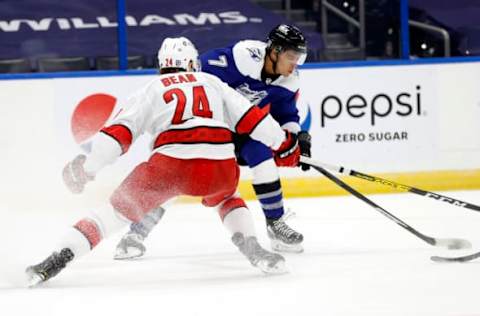 Feb 25, 2021; Tampa, Florida, USA; Tampa Bay Lightning right wing Mathieu Joseph (7) shoots as Carolina Hurricanes defenseman Jake Bean (24) defends during the third period at Amalie Arena. Mandatory Credit: Kim Klement-USA TODAY Sports