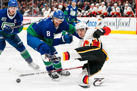 Christopher Tanev of the Vancouver Canucks knocks down Johnny Gaudreau. (Photo by Rich Lam/Getty Images)