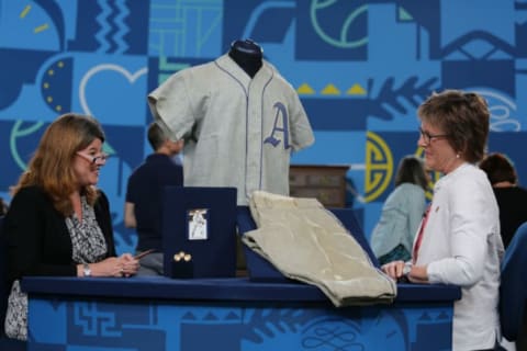 Antiques Roadshow appraiser Leila Dunbar (L) examines a Randy Gumbert baseball uniform.