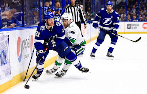 TAMPA, FLORIDA – JANUARY 13: Brayden Point #21 of the Tampa Bay Lightning and Tyler Motte #64 of the Vancouver Canucks fight for the puck during a game at Amalie Arena on January 13, 2022 in Tampa, Florida. (Photo by Mike Ehrmann/Getty Images)