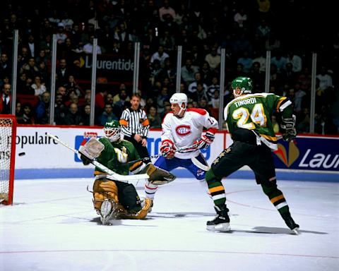 MONTREAL – CIRCA 1980: Mike Keane #12 of the Montreal Canadiens shoots the puck past goaltender Jon Casey #30 and defenseman Mark Tinordi #24 of the Minnesota North Stars in a game at the Montreal Forum circa 1980 in Montreal, Quebec, Canada. (Photo by Denis Brodeur/NHLI via Getty Images)