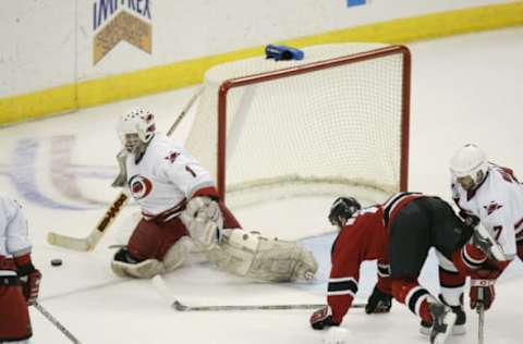 RALEIGH-APRIL 17: Arturs Irbe #1 of the Carolina Hurricanes saves a shot while John Madden #11 of the New Jersey Devils is upended during game one of the Stanley Cup playoffs at the Entertainment and Sports Arena in Raleigh, North Carolina on April 17, 2002. The Hurricanes won 2-1. (Photo by Craig Jones/Getty Images/NHLI)